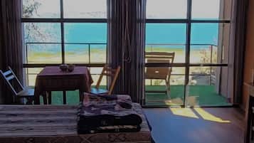 Un dormitorio con un ventanal grande, una cama, una mesa y una silla.
