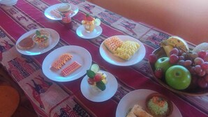 A table set with various dishes including fruit, a bowl of grapes, and a plate with a green apple. - Casa de Primo (Capachica)