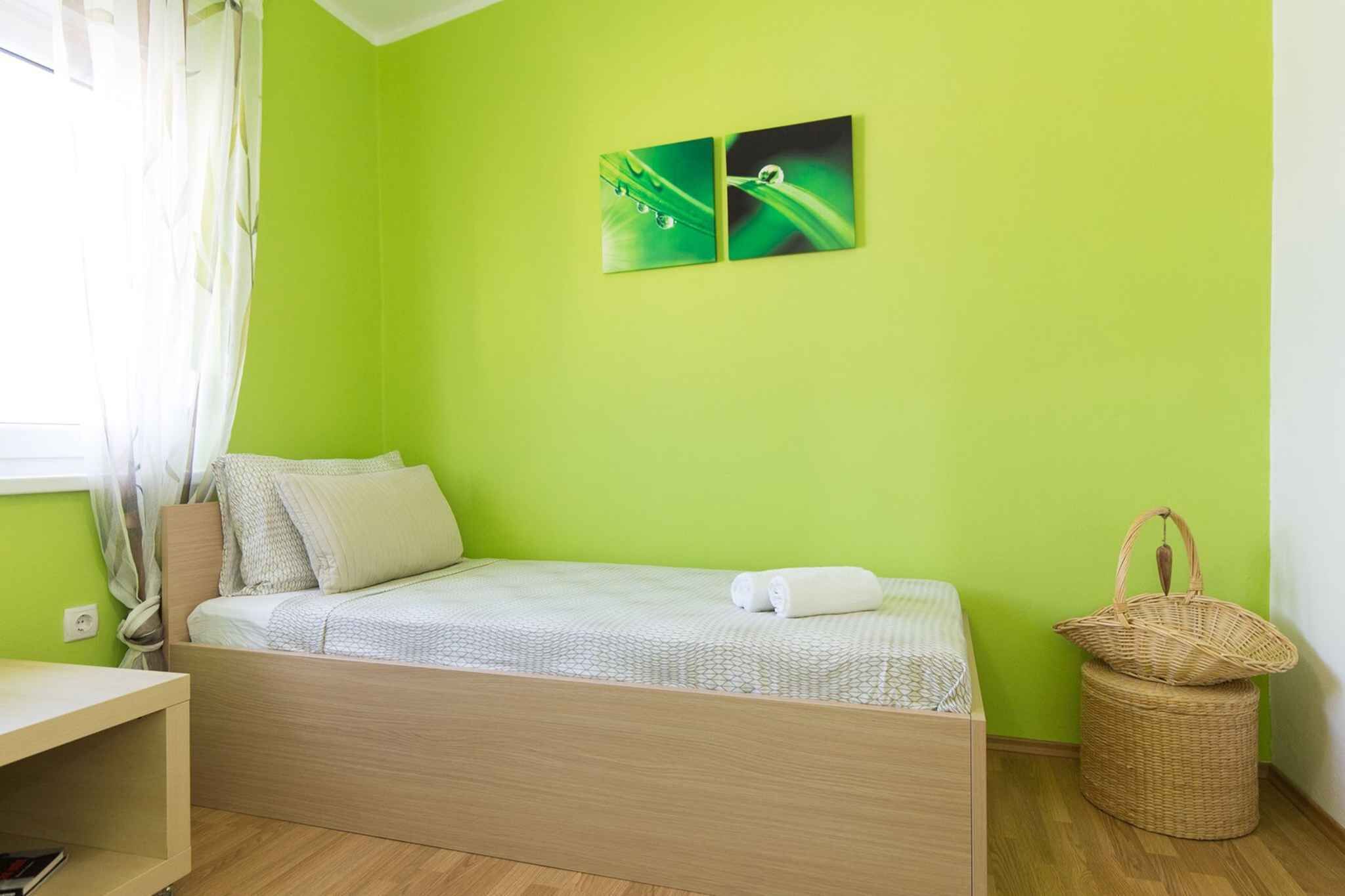 Une chambre comprenant un lit, un petit bureau, un panier et deux œuvres d’art murales.