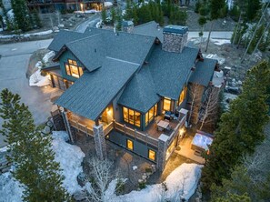 Une grande maison à étages, avec une façade en pierre, de nombreuses fenêtres et un espace extérieur bien éclairé.