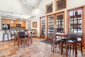 A spacious kitchen with wooden cabinets, a dining area with chairs, and large windows with a view.