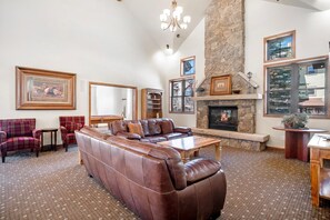 A spacious living room with a large leather sofa, a fireplace, and a stone accent wall.