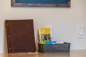 Un classeur à couverture en cuir marron portant l’inscription « VISITEZ Winter Park » et une carte des sentiers de randonnée, le tout posé sur une table avec un panier contenant des documents.