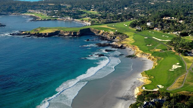 An aerial view of a coastal golf course with a beach, ocean, and forested hills in the background. - Modern Cozy Pebble Beach Studio with Premium Amenities and WiFi (Del Monte Forest)