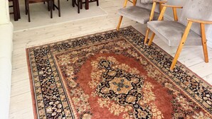 Un espace repas comprenant une table et des chaises, un lustre, un tapis à motifs et un canapé.