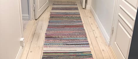 A hallway with a colorful striped rug, white doors, and wooden flooring.
