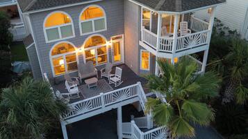 Une maison à deux étages dotée d’un balcon, d’un espace extérieur aménagé pour s’asseoir et d’un intérieur bien éclairé.
