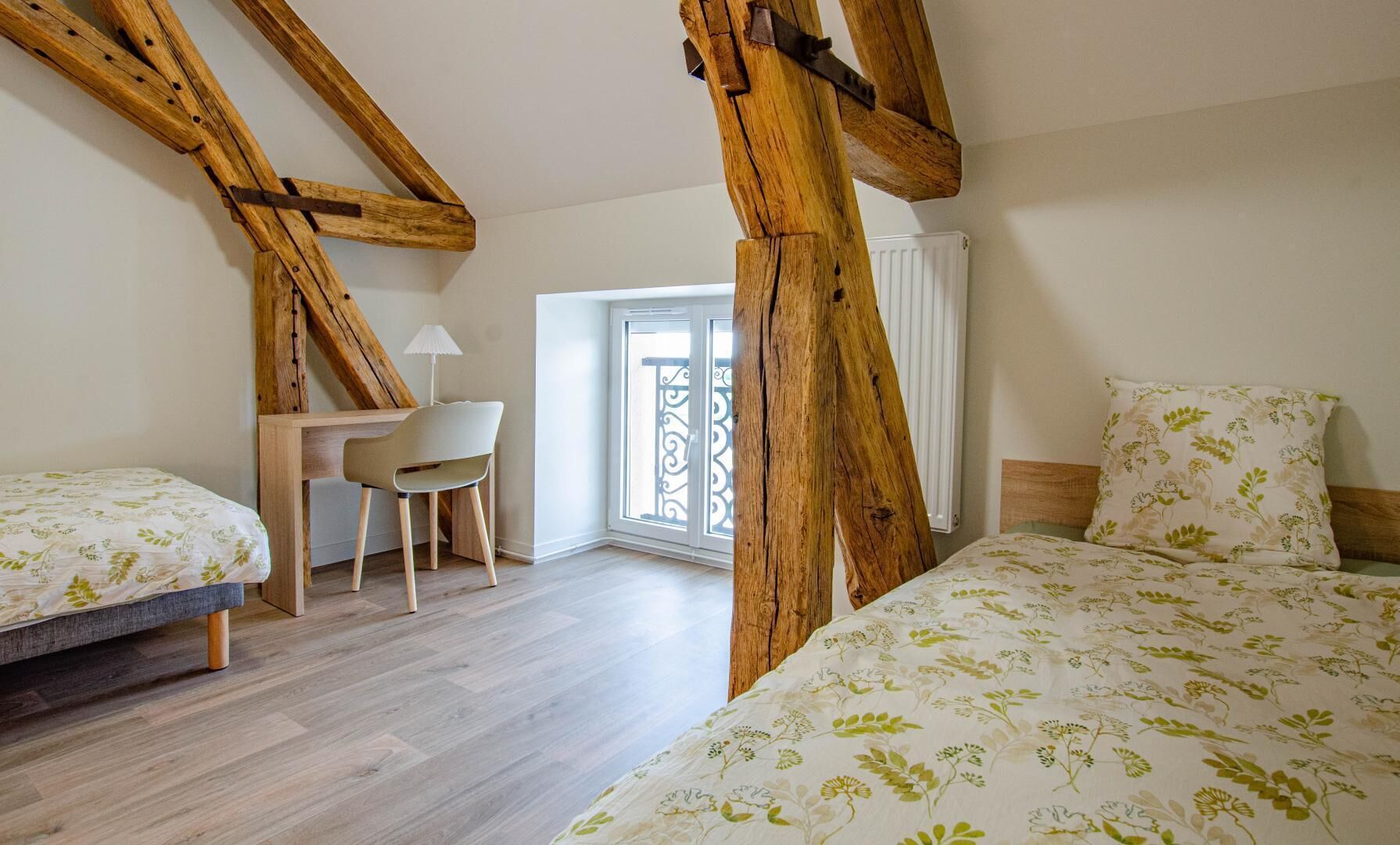 A bedroom with two beds, a desk, and a chair.