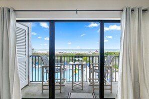 A balcony with a view of the beach, a pool, and two chairs. - Direct Oceanfront Condo W/ Private Balcony & BBQ Grills (Cocoa Beach)