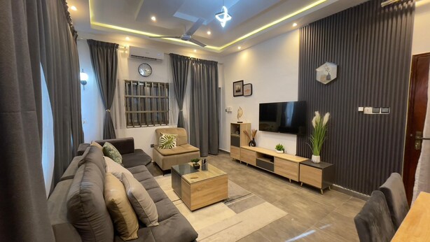Una sala de estar moderna con un sofá, una mesa de centro, un televisor y elementos decorativos.