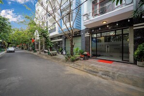 A street view of a building with a storefront and a parked car. - Charming 4-bedroom house with AC and WiFi in enchanting Đà Nẵng (Đà Nẵng)