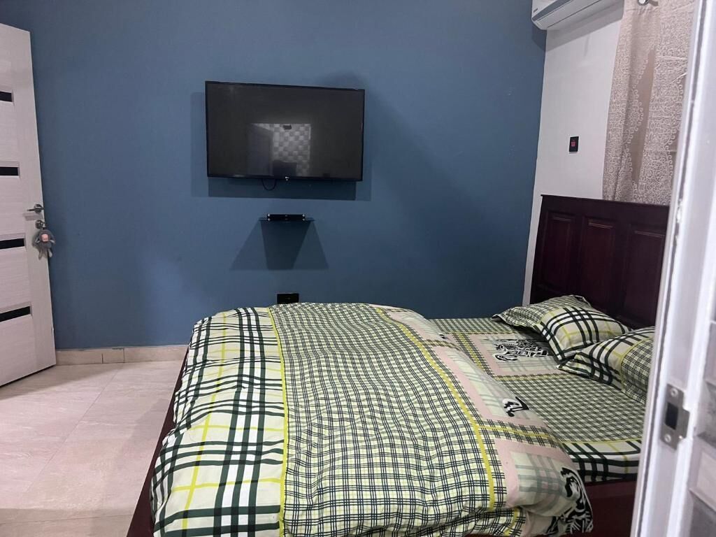 Ein Schlafzimmer mit einem Bett, einem an der Wand montierten Fernseher und einer Tür.