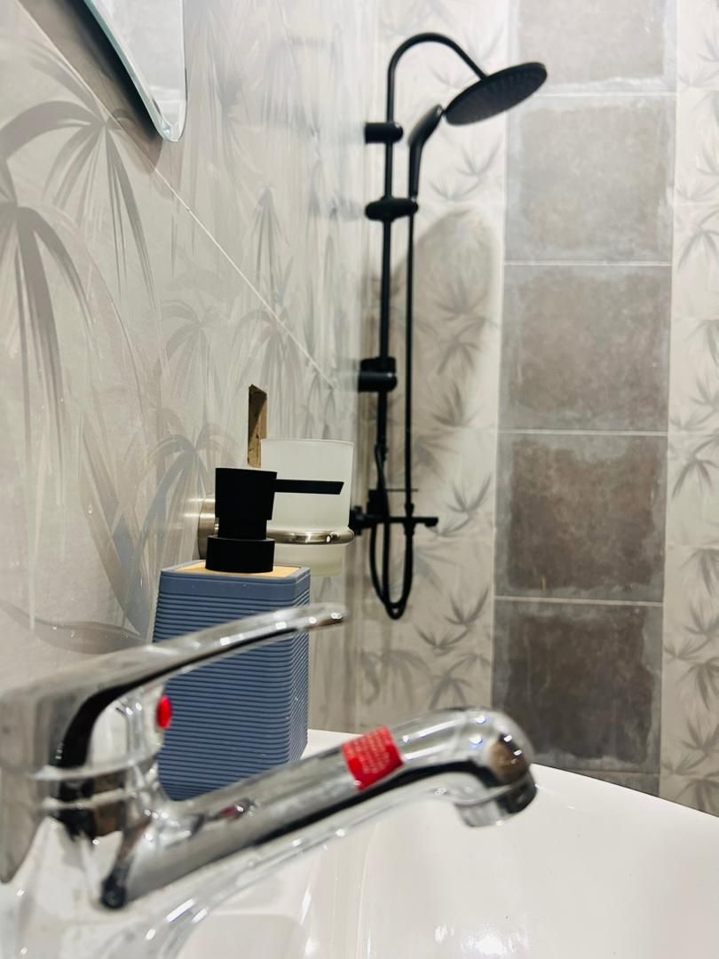 Ein Badezimmer mit Dusche, Waschbecken und Spiegel.