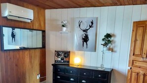 Un dormitorio con cama, cómoda, espejo y aire acondicionado instalado en la pared.
