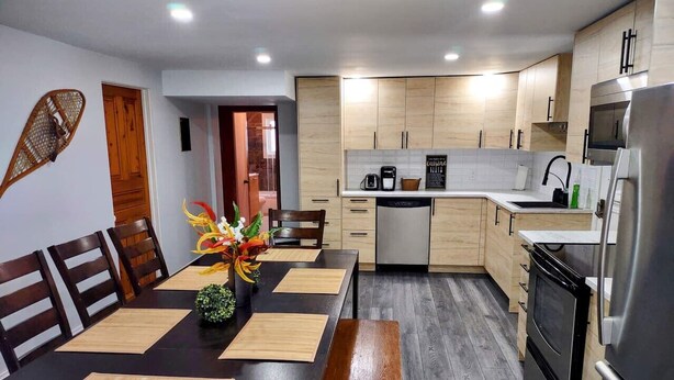 Una cocina moderna con armarios de madera, horno empotrado y refrigerador de acero inoxidable.
