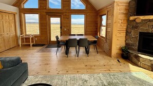 Una habitación espaciosa con techo alto, paredes de madera y ventanas amplias que ofrecen vistas al exterior.