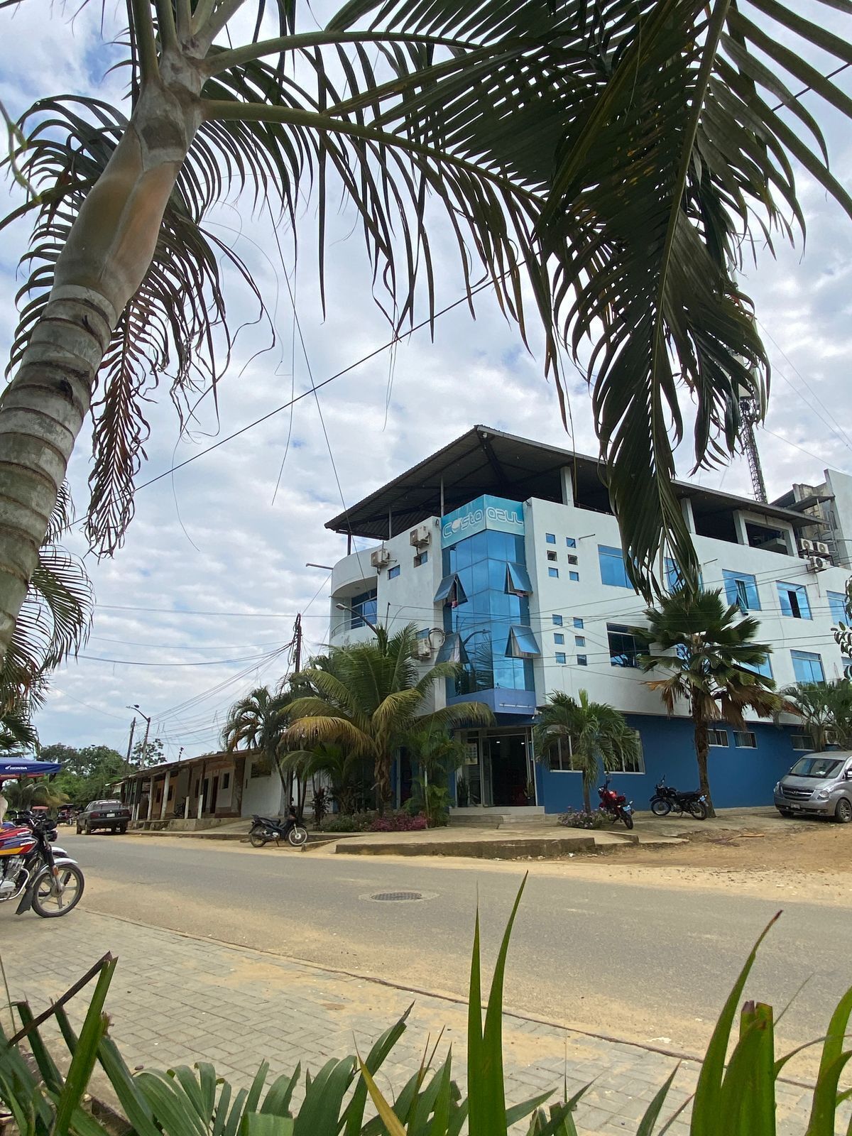 Un edificio de varios pisos con fachada azul y blanca, que presenta un amplio ventanal en la planta baja.