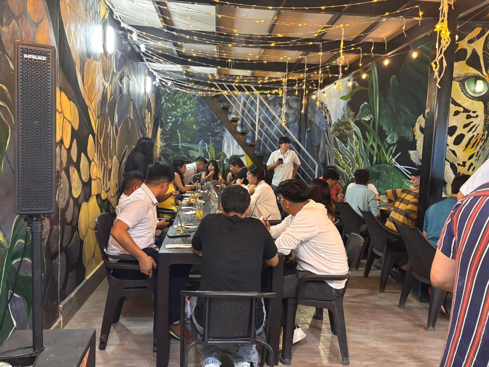 Un restaurante con un mural, luces colgantes y un altavoz.