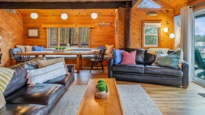 A cozy cabin interior with a wooden interior, a dining area, and a seating area with a view.