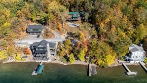 An aerial view of a lakeside property with multiple buildings, a dock, and a boat.