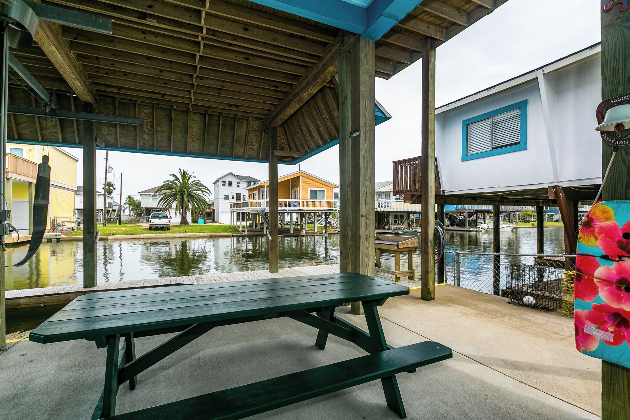 A covered picnic table with a view of a waterfront area, including a dock and buildings in the background.