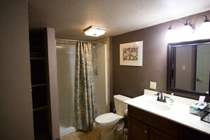 Ein Badezimmer mit Dusche, Toilette, Waschbecken und Spiegel.