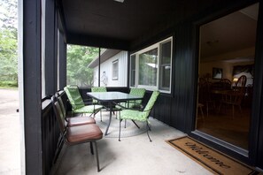 Relax in this serene outdoor seating area with a table and chairs, surrounded by large windows and a welcoming entrance.