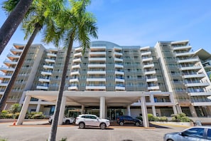 A multi-story hotel with balconies, a covered entrance, and parked cars. - 3-Bedroom Resort-Style Water Views | King Beds, Pool, Balcony (Darwin City)