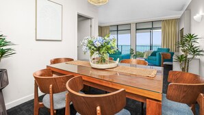 Un comedor moderno con una mesa de vidrio, sillas de madera y un centro de mesa con flores.
