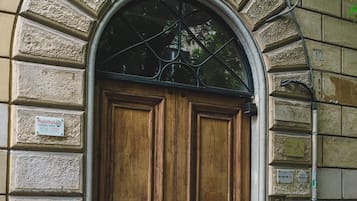 Un'ampia porta doppia in legno con cornice metallica, incassata in un arco in pietra.