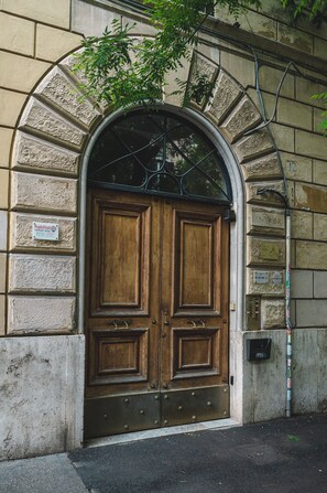 A large wooden double door with a metal frame, set within a stone archway.