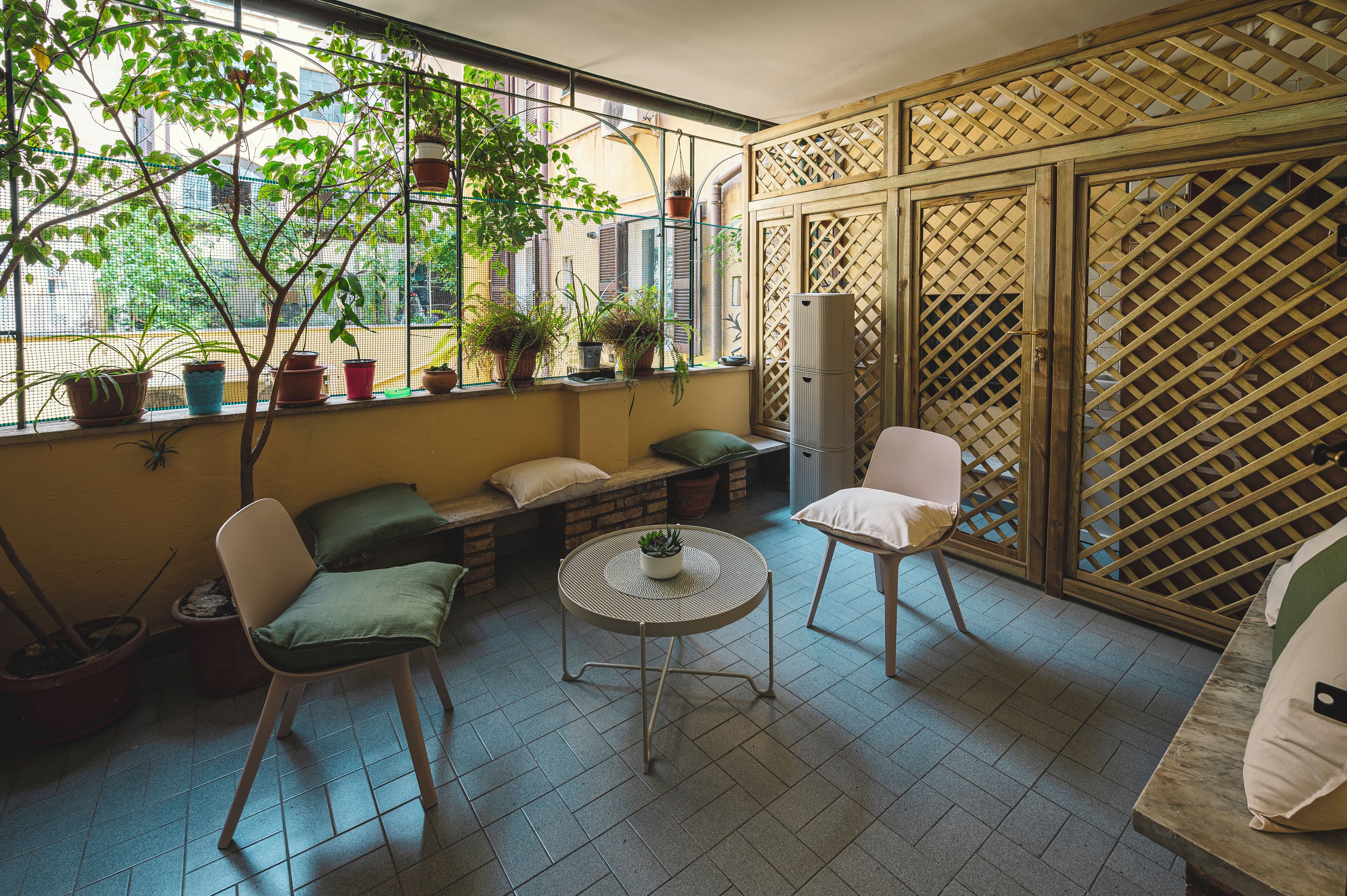 Un balcone con angolo salotto, piante in vaso e vista sulla città.