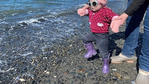 A child playing on a rocky beach with the ocean in the background. - Paradise Suites Eagles Nest Apt C (Homer)
