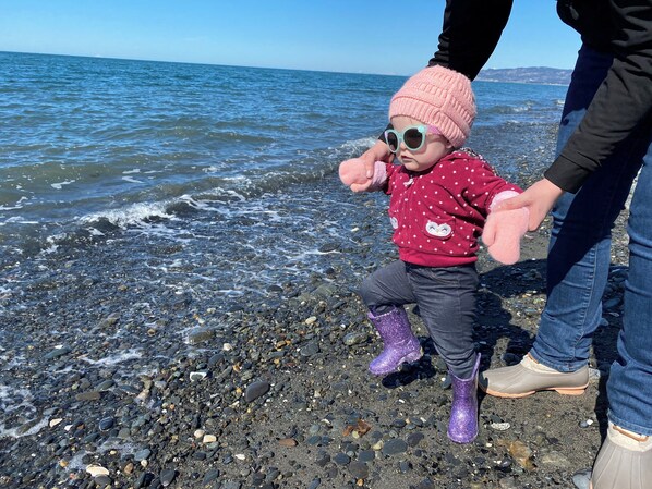 Un niño jugando en una playa rocosa con el océano al fondo.