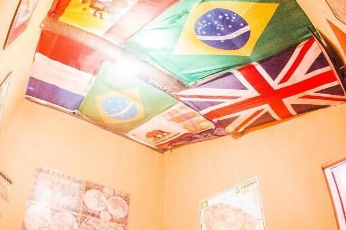 A bedroom with a bed, a wall with a map, and a ceiling with flags.