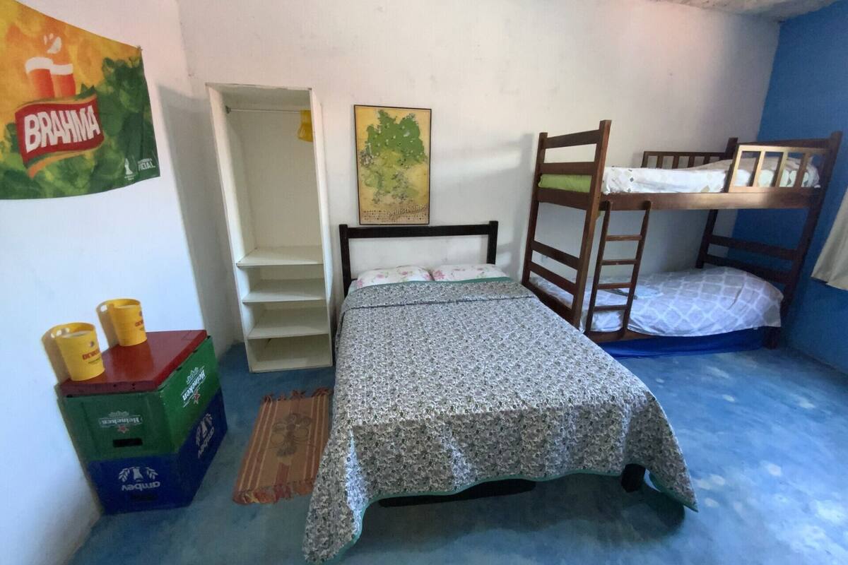 A small, single-room accommodation with a bunk bed, a wardrobe, and a bed with a floral bedspread.