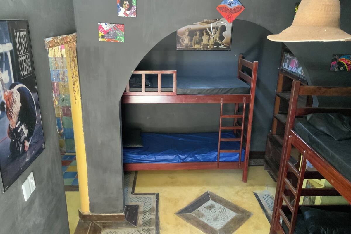 A bunk bed room with posters, a hat, and a ladder.