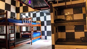 A dormitory room with bunk beds, checkered walls, and a ceiling light. - Trip Hostel e Pousada (Jericoacoara)