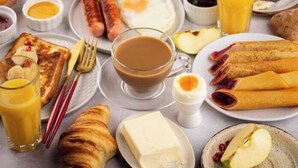 A breakfast setting with various foods including toast, eggs, sausages, and pastries. - Trip Hostel e Pousada (Jericoacoara)