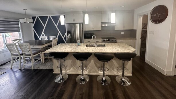 A modern kitchen with a central island, stainless steel appliances, and bar stools. - A/C, Fenced backyard , BBQ grill, pets welcome (Edmonton)