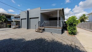 A modern two-story house with a covered porch and a small staircase leading to the entrance. - Townsville Golf Course Haven | 2 Bedroom Stay with Parking (Rosslea)