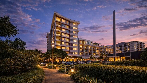 A multi-story hotel with a modern design, featuring balconies on each floor, a central pathway, and a tall structure to the right. - Holborn 2BR Apartment with Pool, Gym & Parking in Townsville CBD (Townsville City)