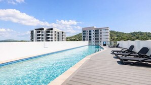 A rooftop swimming pool with lounge chairs and a view of two buildings in the background. - Holborn 2BR Apartment with Pool, Gym & Parking in Townsville CBD (Townsville City)