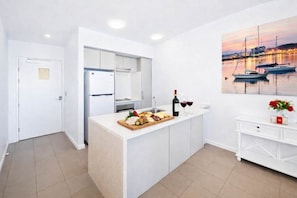 Une cuisine moderne dotée d’un îlot central, d’un coin repas et offrant une vue sur les bateaux sur l’eau.