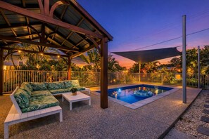 A covered outdoor area with a pool, a sofa, and a table. - 3BR Family Home w/ Private Pool | Pet-Friendly | West End (West End)