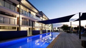 Ein modernes Hotel mit Schwimmbad, mehreren Balkonen und einem überdachten Gang.