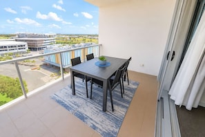 Ein Balkon mit Tisch und Stühlen und Blick auf Gebäude, dazu ein klarer Himmel.