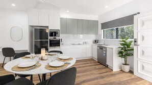 Una cocina moderna con armarios blancos, horno empotrado y lavavajillas.