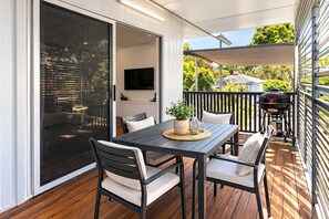 A deck with a table and chairs, a grill, and a TV in the background. - Windsor Charm – 2BR Hermit Park Unit near Townsville CBD (Hermit Park)