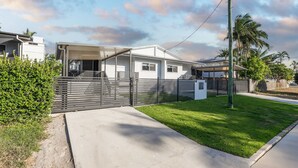 Una casa moderna con un porche cubierto, un patio cercado y un césped bien cuidado.